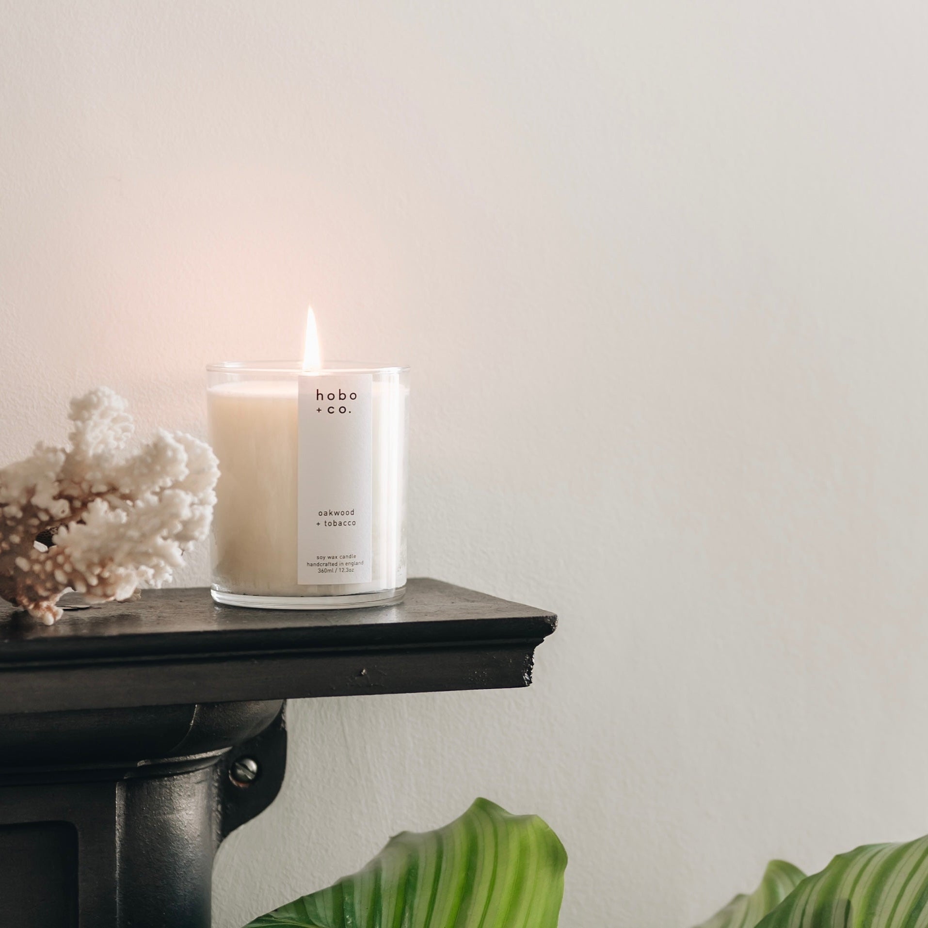 Large Oakwood and tobacco soy candle lit on a mantlepiece