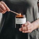 Person lighting a candle labeled 'hobo & co.'