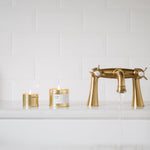 Gold faucet and candles on a white countertop