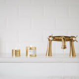 Gold faucet and candles on a white countertop