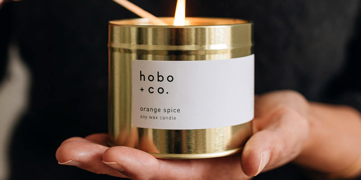 Christmas orange spice festive candle being lit with a match held in hands