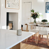 Ceramic candle pot on kitchen worktop with a woodburning stove and dining table behind