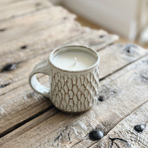 close up of ceramic mug candle on rustic table