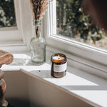 raspberry and peppercorn medium candle lit on a sunny window sill 