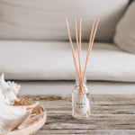 raspberry and peppercorn reed diffuser in living room on a rustic table top