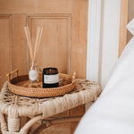 rest medium essential oil candle on a bedroom side table with diffuser and door behind