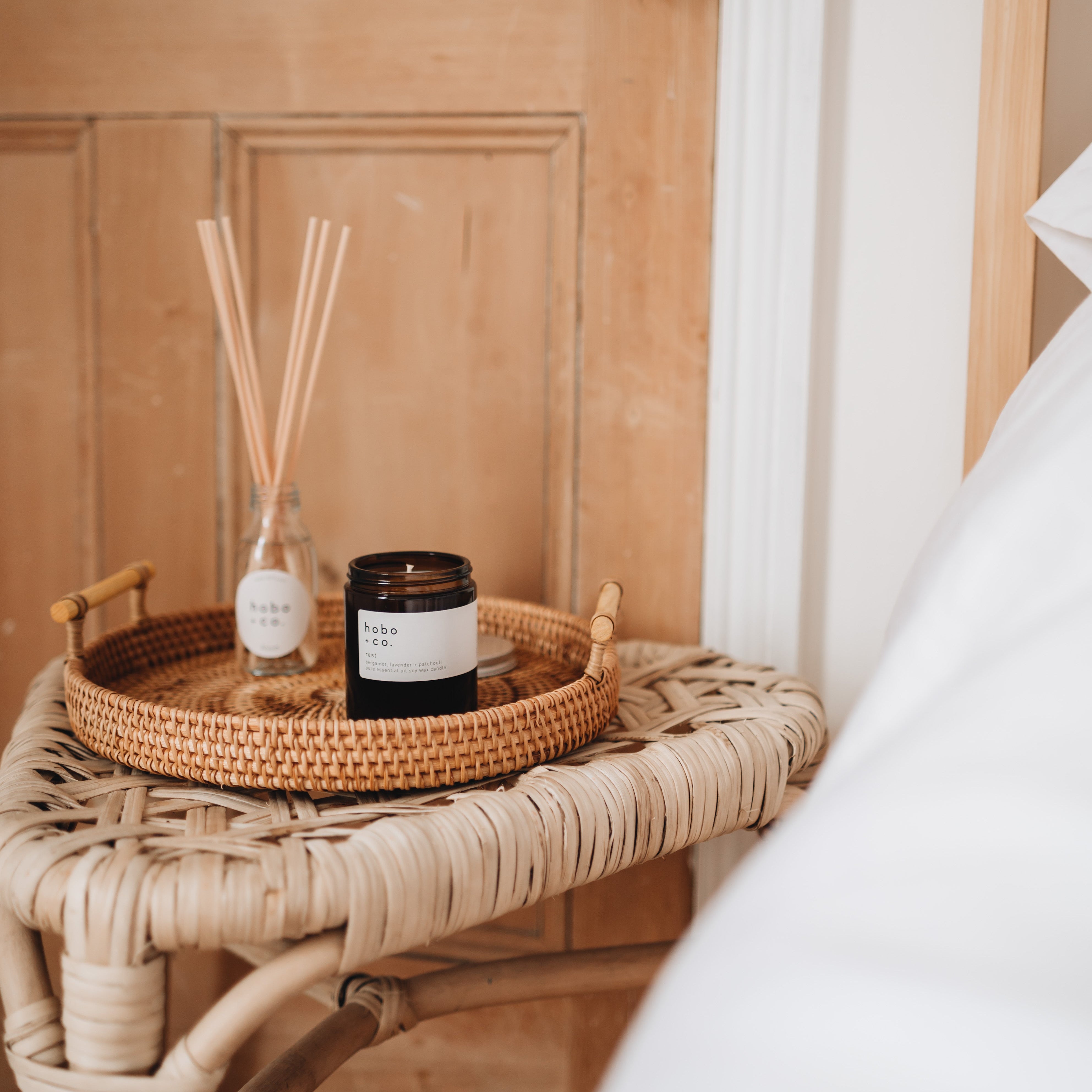 rest medium essential oil candle on a bedroom side table with diffuser and door behind
