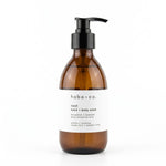 An amber glass pump bottle of hobo + co. hand and body wash with a white label and black pump dispenser, set against a plain white background.