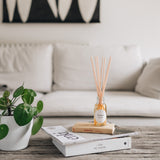 roam reed diffuser on a rustioc living room table with a cream sofa behind