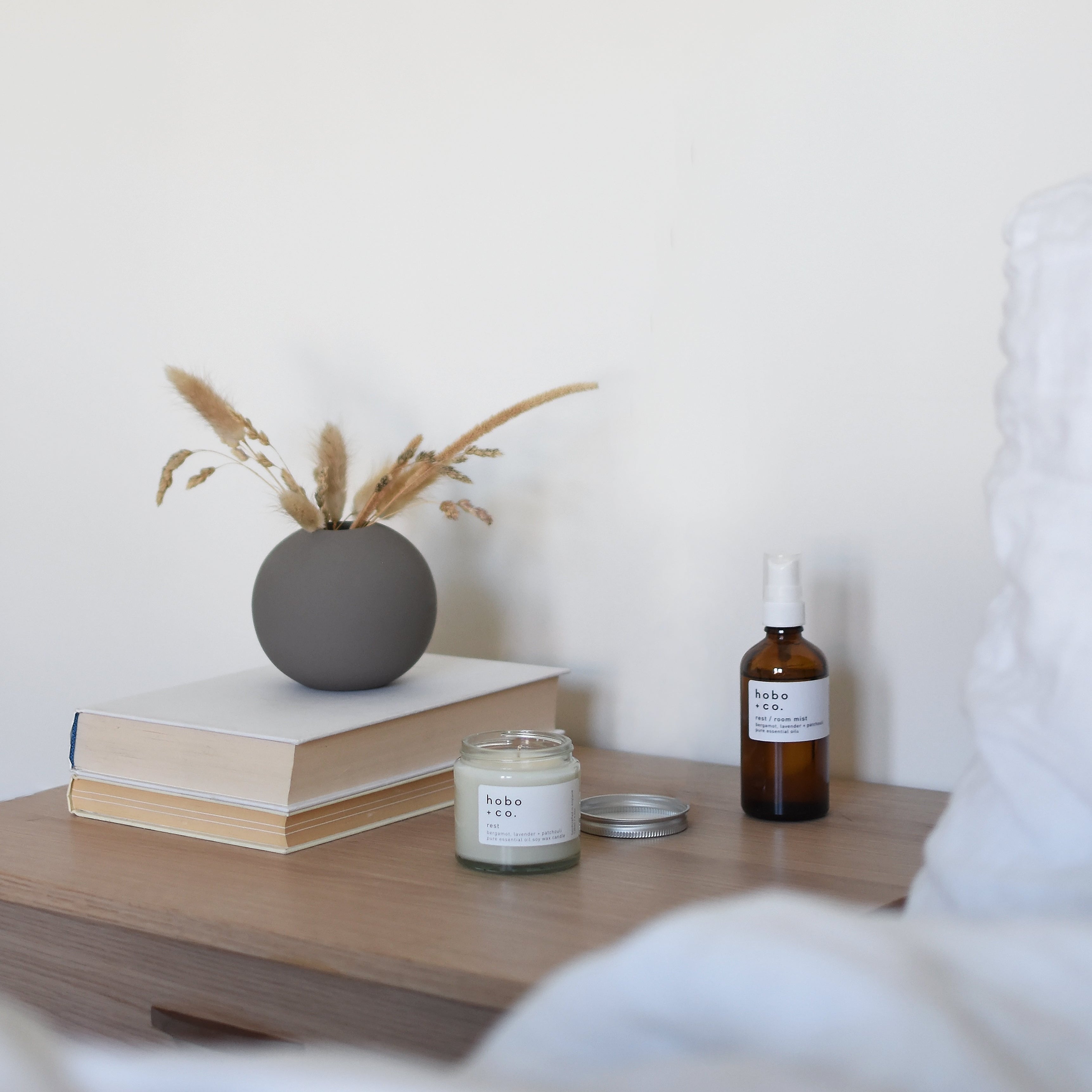 room spray and pillow list with a candle on a cosy bedside table from hobo and co