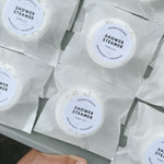 Multiple shower steamers in packaging with a hand holding the tray. Eco-friendly handmade shower steamer gift